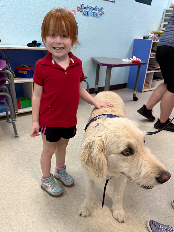 Adelen pets a visiting therapy dog at Connections Education Center for autism