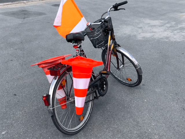 Ein Fahrrad mit wehender Fahne und Verkehrshütchen am Fahrradkorb