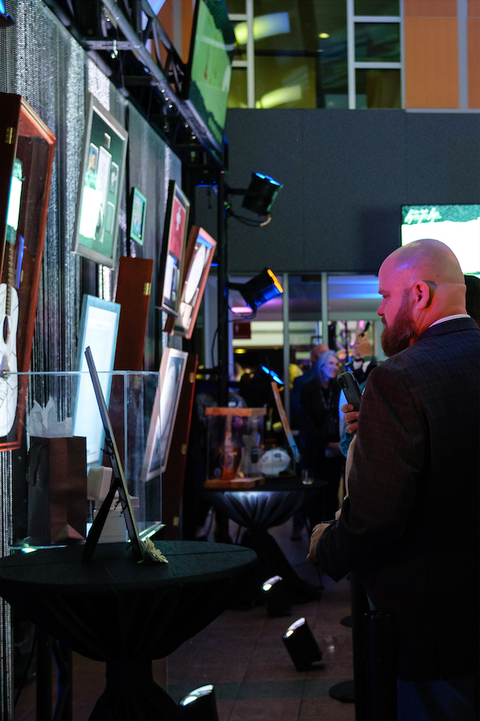 A man browsing the auction items hanging on the wall.