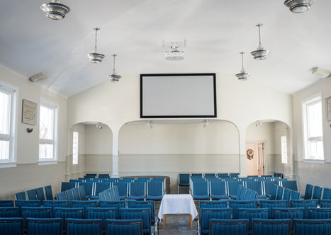 Empty auditorium with blue seating and a projector screen Ottawa Gospel Hall.