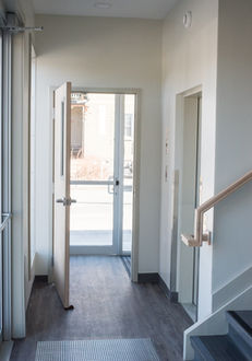 Interior hallway with open door, stairs, and natural light shining through. Ottawa Gospel Hall.