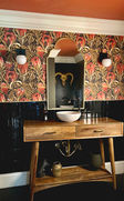 Airbnb powder room design with bold floral wallpaper, arched mirror, and wood vanity for a Nashville short term rental