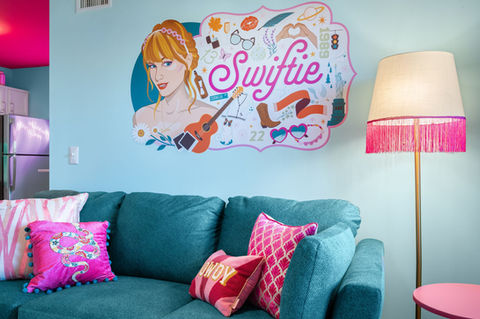 Music-themed Airbnb living space in North Nashville featuring teal sofa, pink accents, and custom wall art