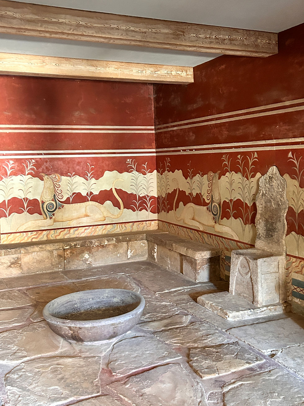 Thronsaal im Palast von Knossos auf Kreta mit roten Wandmalereien, weißen Lilien und mythischen Symbolen. Im Vordergrund eine runde Steinschale, rechts der berühmte steinerne Thron