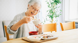 美味しそうに食事をする高齢の女性