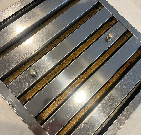 Stove top hood covered in grease before cleaning.