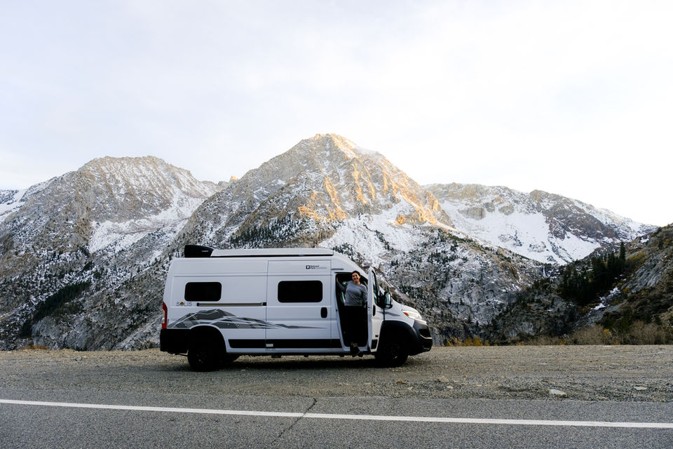 Person by camper van with snowy mountains