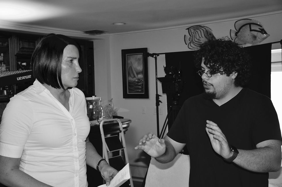A woman and man in discussion indoors, surrounded by filming equipment and marine-themed decor. Both seem focused and engaged. Black and white image.