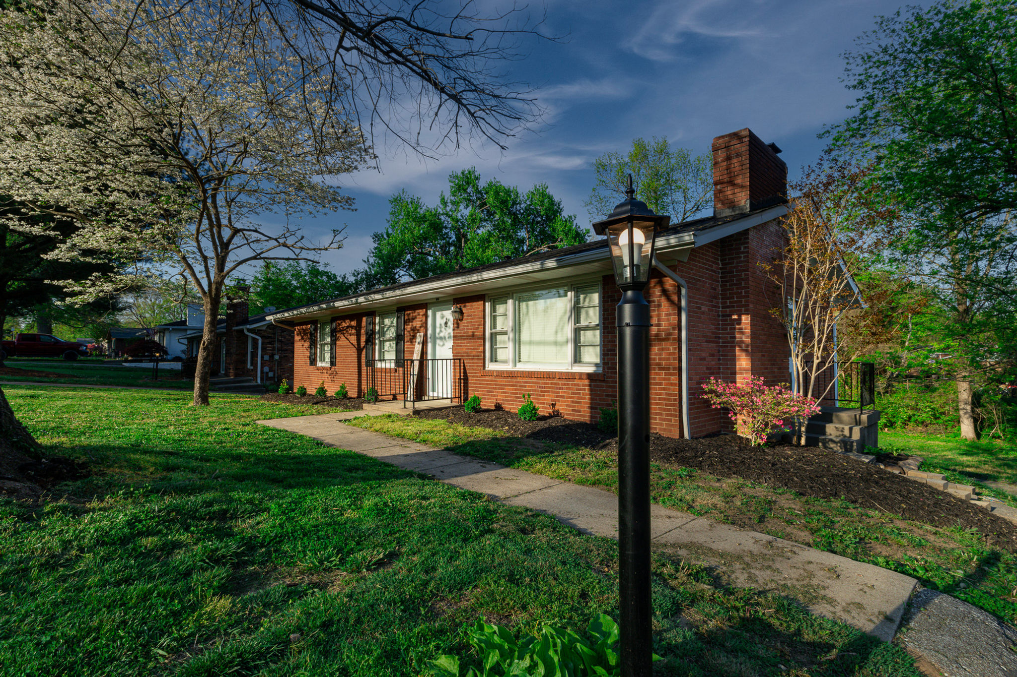 One-story brick house with a green lawn and front walkway.