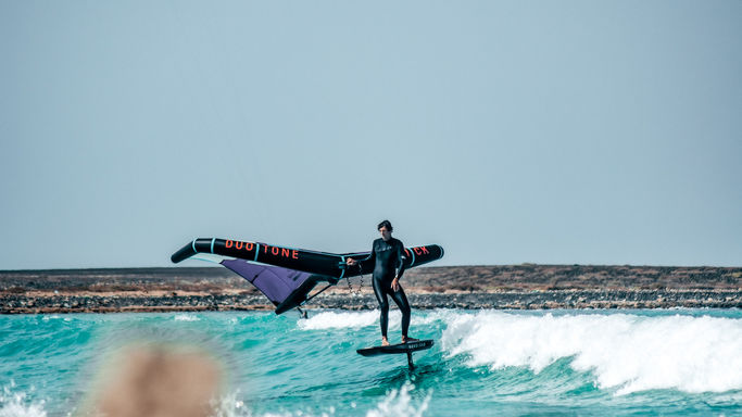 Wingfoiler in einer Welle von türkisem Wasser.