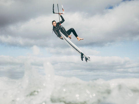 Kitesurferin in der Luft mit Board in der Hand vor der Küste Sylts