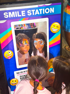Child looking in a mirror admiring fresh face painting at an event.