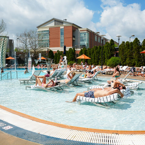 Students laying by the pool in poolside chairs.