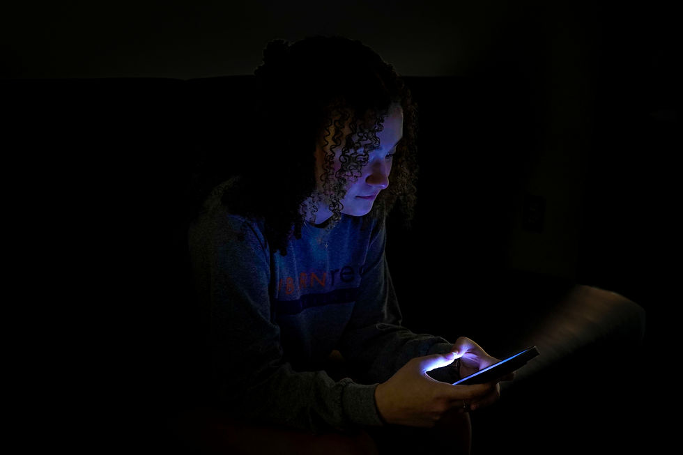 A girl looking at a phone screen that lights up her face.