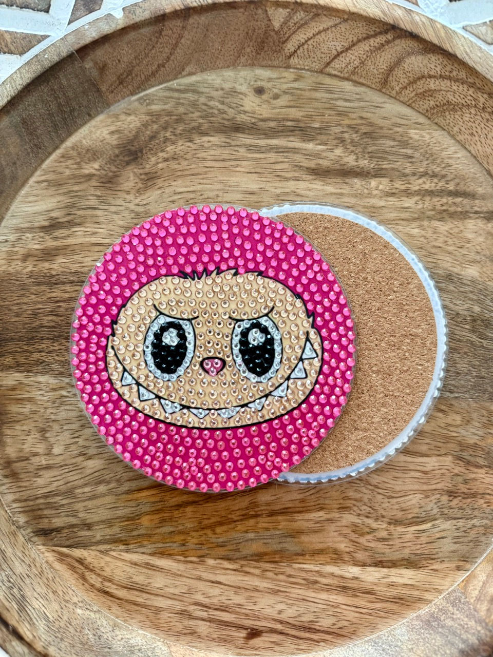 coaster featuring a Labubu character on a hot pink background, designed with sparkling rhinestones and displayed on a stand.