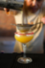 Bartender straining a cocktail at a restaurant bar.