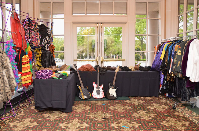 Props and costumes set up for a lip syc battle in a room on tables and racks.