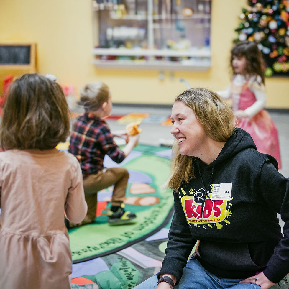 A woman sitting on the floor having fun with kids while serving at Damascus Road during our Kids' Sunday Program in Mt. Airy