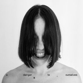 The cover for Lucrecia Dalt's, A Danger to Ourselves album, showing her with black hair covering their face grins intensely in a black-and-white image. Text reads, "a danger to ourselves."