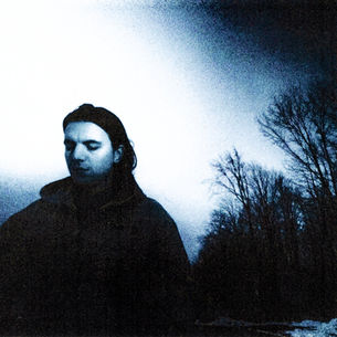 The cover for Hockitay's "buttons" single, showing Hockitay with long hair standing outside against a pale blue sky and leafless trees, creating a moody, somber atmosphere.