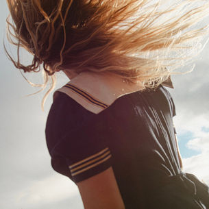 The cover for Lindsey Troy and Deap Vally's "See You on the Other Side" single showing Troy in a navy sailor-style dress, hair whipping in the wind against a bright cloudy sky.