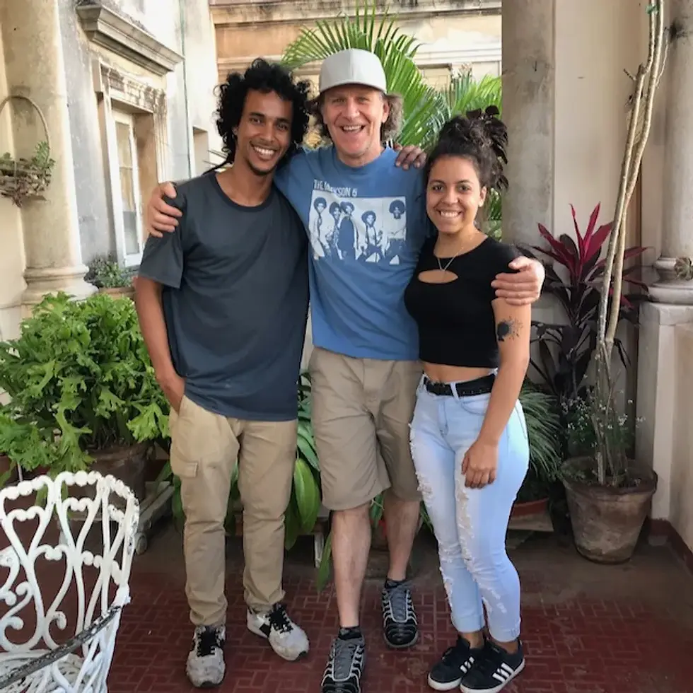 Nic Tee and friends smiling and posing together on a patio with plants. Casual, relaxed atmosphere.