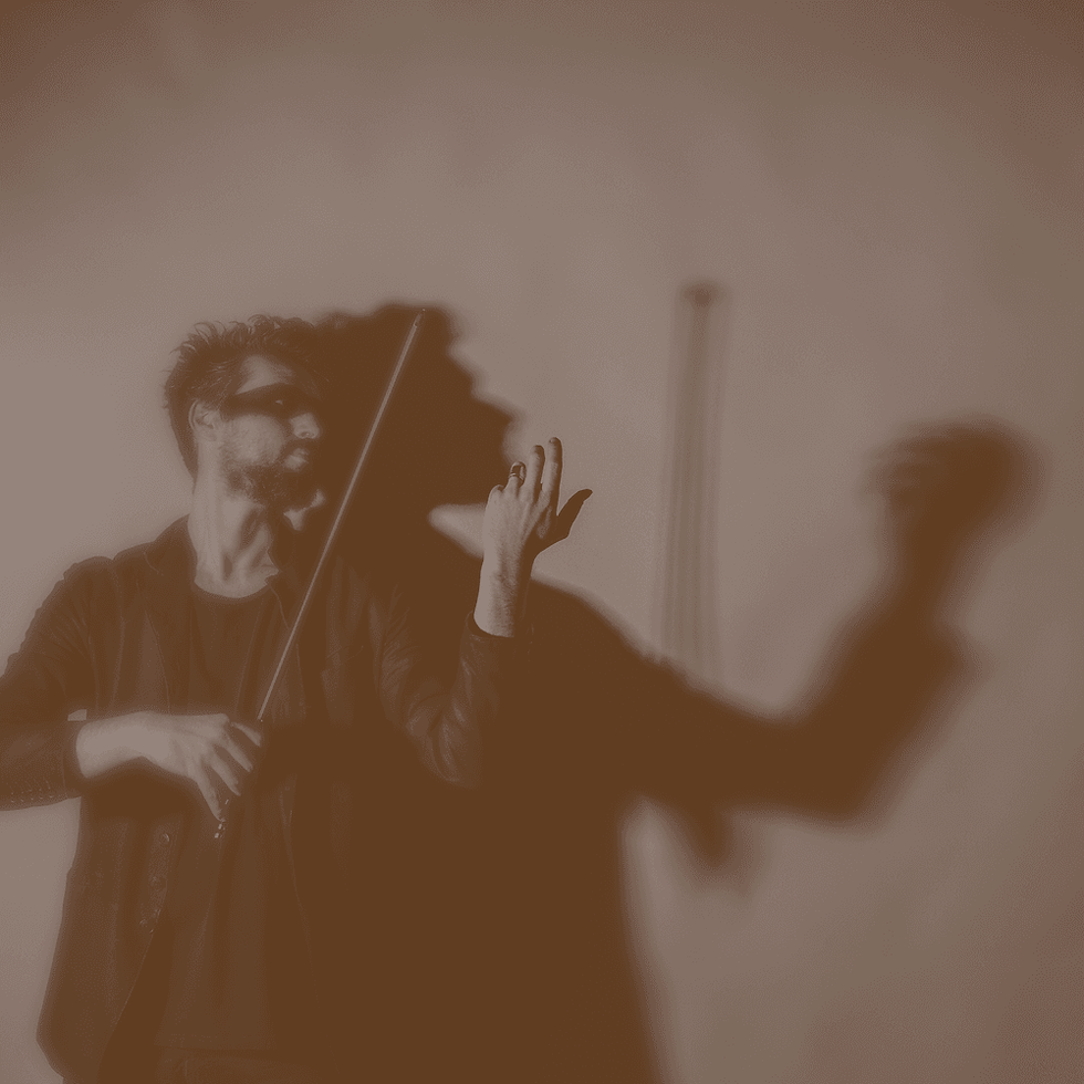 David Handlre playing an invisible violin, casting dramatic shadow on wall. Sepia tone creates a moody, artistic atmosphere.