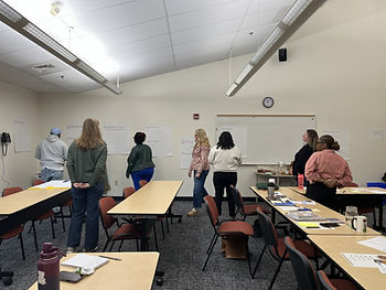 One man and six women gather around large sticky notes placed on the wall.