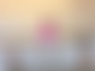 Una mujer de cabello negro con una sudadera rosa sonríe detrás de una mesa que dice "Black Infant Thrive" (Los bebés negros prosperan).