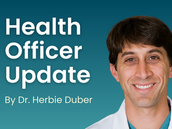 A man with dark hair wearing a white lab coat smiles at the camera. Text reads: Health Officer Update by Dr. Herbie Duber.