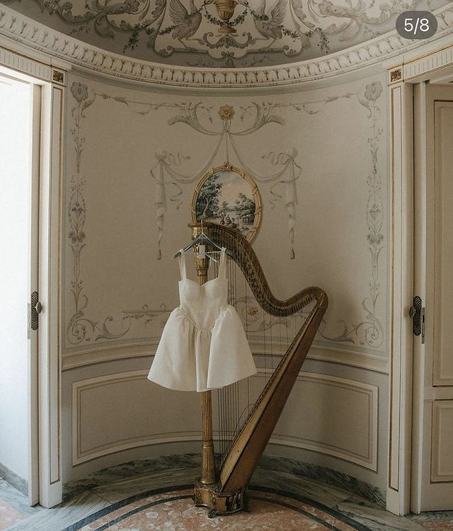 Chique en trending bruidsjurk hangend aan een harp voor luxe bruiloft