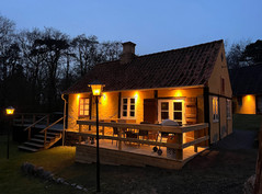 Rævehuset oplyst med terrasse i aftenstemning.
