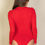 Thumbnail: A person with long brown hair wearing a red long-sleeve bodysuit, photographed from the back.