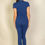 Thumbnail: A woman is standing with her back to the camera, wearing a fitted blue short-sleeve top and matching blue pants against a pla