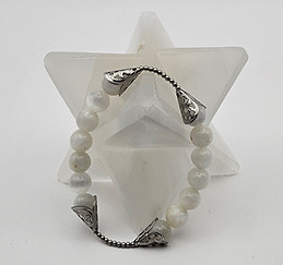 Bracelet en pierre de lune avec embouts argentés finement ouvragés, posé autour d’une étoile de cristal de sélénite blanche s