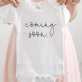 a woman holding a baby's shirt that says
