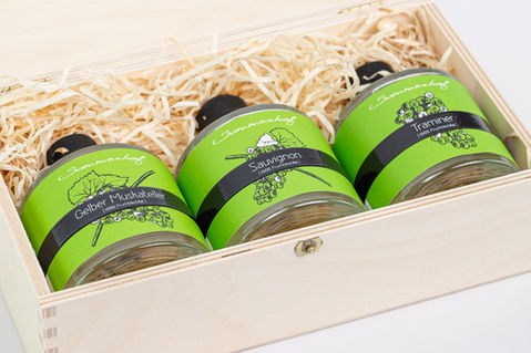 Holzkiste mit drei runden Schnapsflaschen mit grünem Etikett