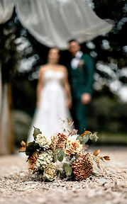 Brautstrauß und dahinter das Brautpaar.