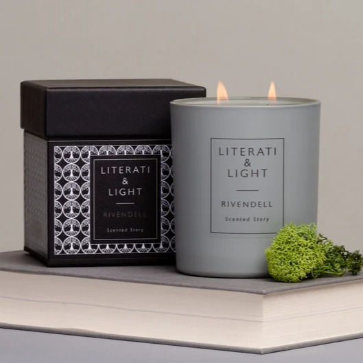 A lit candle and it's presentation book next to it sat upon a closed book.