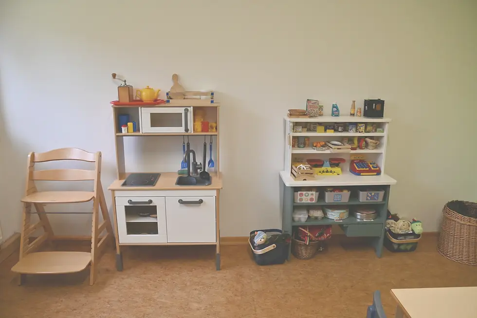Kinderküche und Kaufladen in einem Spielraum mit Küchenutensilien und Spiellebensmitteln.