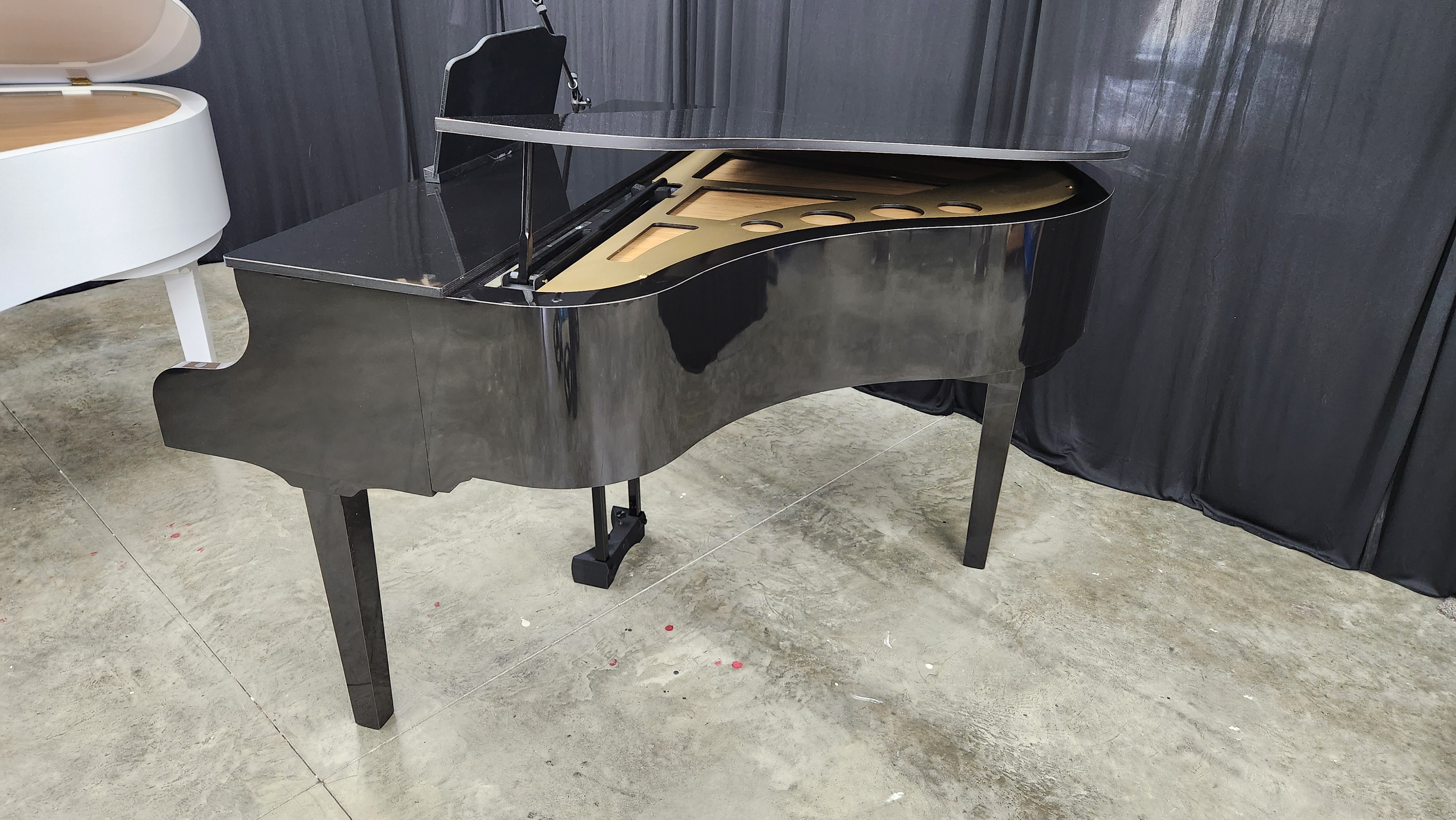 A black Keyhole grand piano shell in the showroom