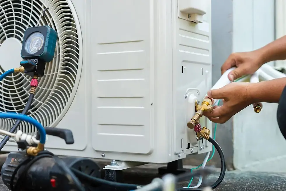 Technician connecting refrigerant lines to a heat pump outdoor unit with a vacuum pump and gauge attached