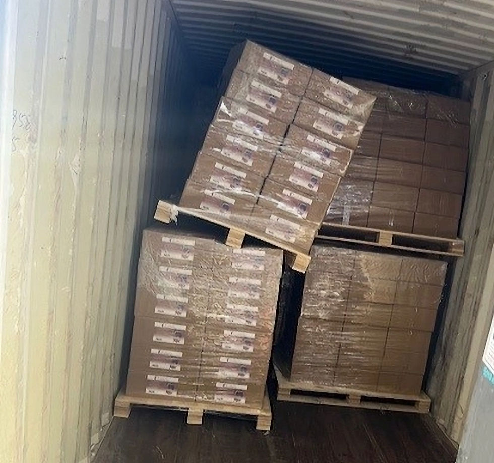 Stacked pallets of boxes in a shipping container, tilted and leaning to one side. Boxes are wrapped in plastic.