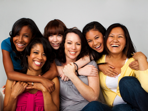 A diverse group of women laughing and embracing together, representing community, joy, and mutual support in the birth worker community.