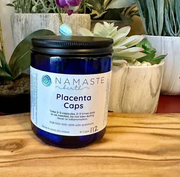 Cobalt bottle containing encapsulated placenta on olive wood slab.