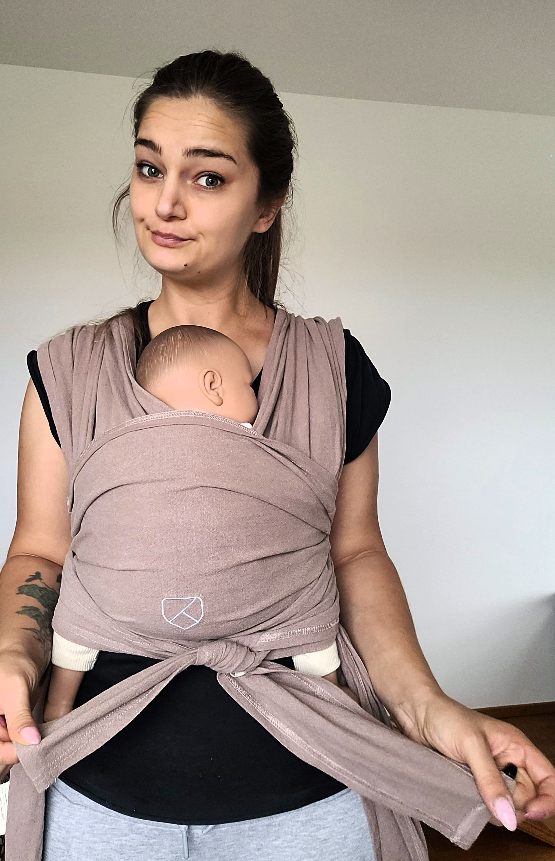 Frau trägt Baby in der Koala Cuddle band 2 Babytrage und testet diese.