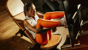 Fit female athlete performing a leg press exercise in a gym, engaging the quadriceps and hamstrings
