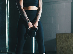 Woman gripping a kettlebell handle with both hands in a gym