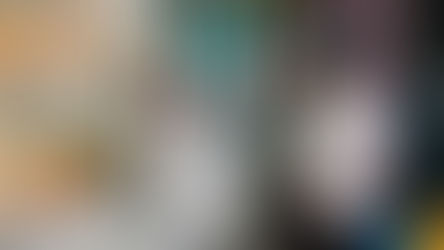 香港入境处——一名身穿围裙的男子正在食品摊位前用泡沫塑料盒盛面条，摊位周围堆放着许多容器。橱窗里展示着色彩鲜艳的海报和菜单。