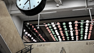 香港商业：建筑物内的时钟，天花板上挂着五彩缤纷的灯笼。水泥楼梯上标有“上”和“下”的指示牌。